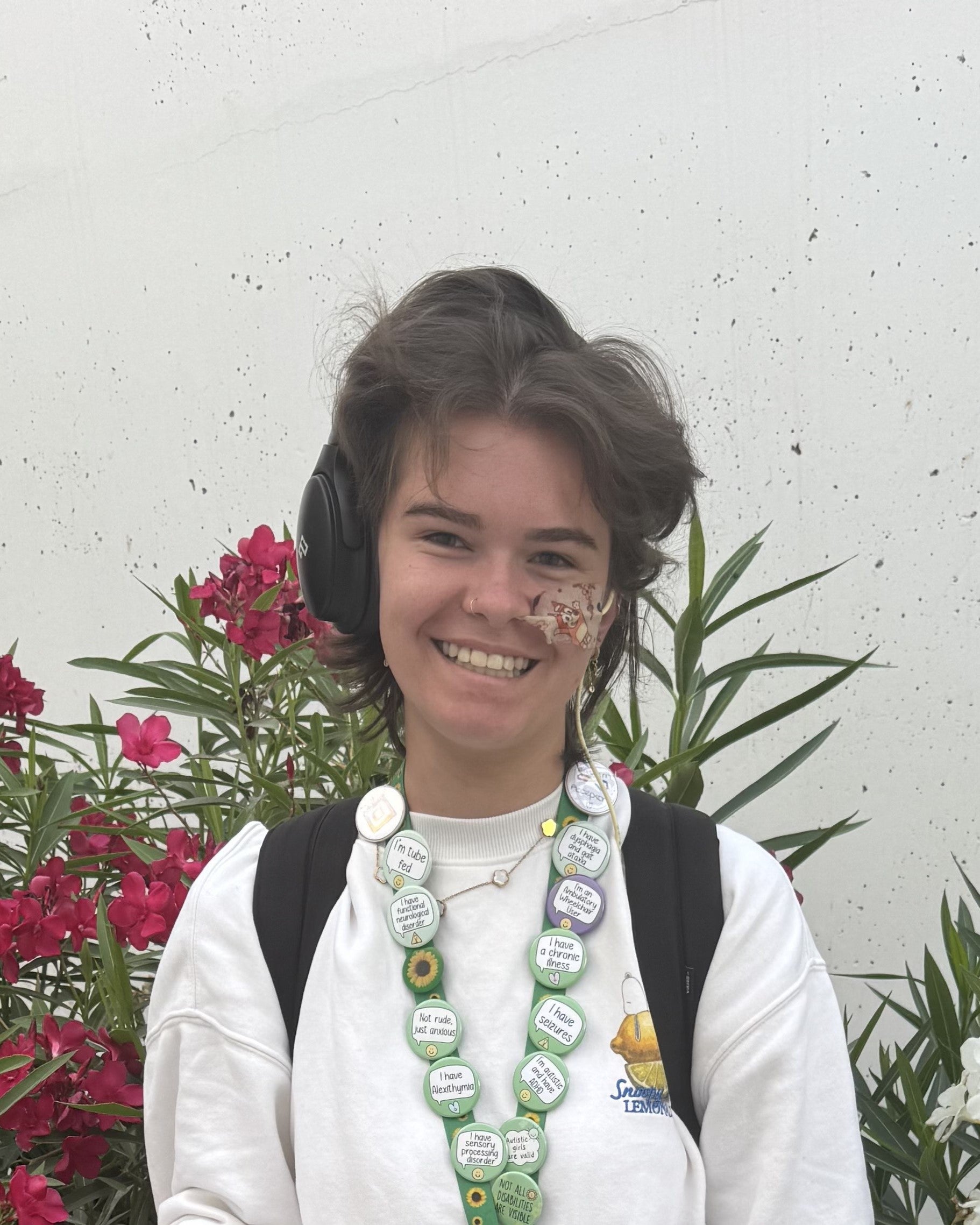 Photo of Charlotte smiling and holding her bag. She has a black hair and wears a white sweater.