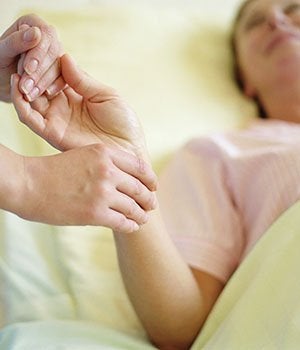 Woman being cared for in hospital bed. Critical care