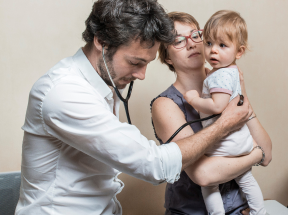 Dr checking on infant being held my mum