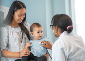 Dr checking on infant with mum by her side