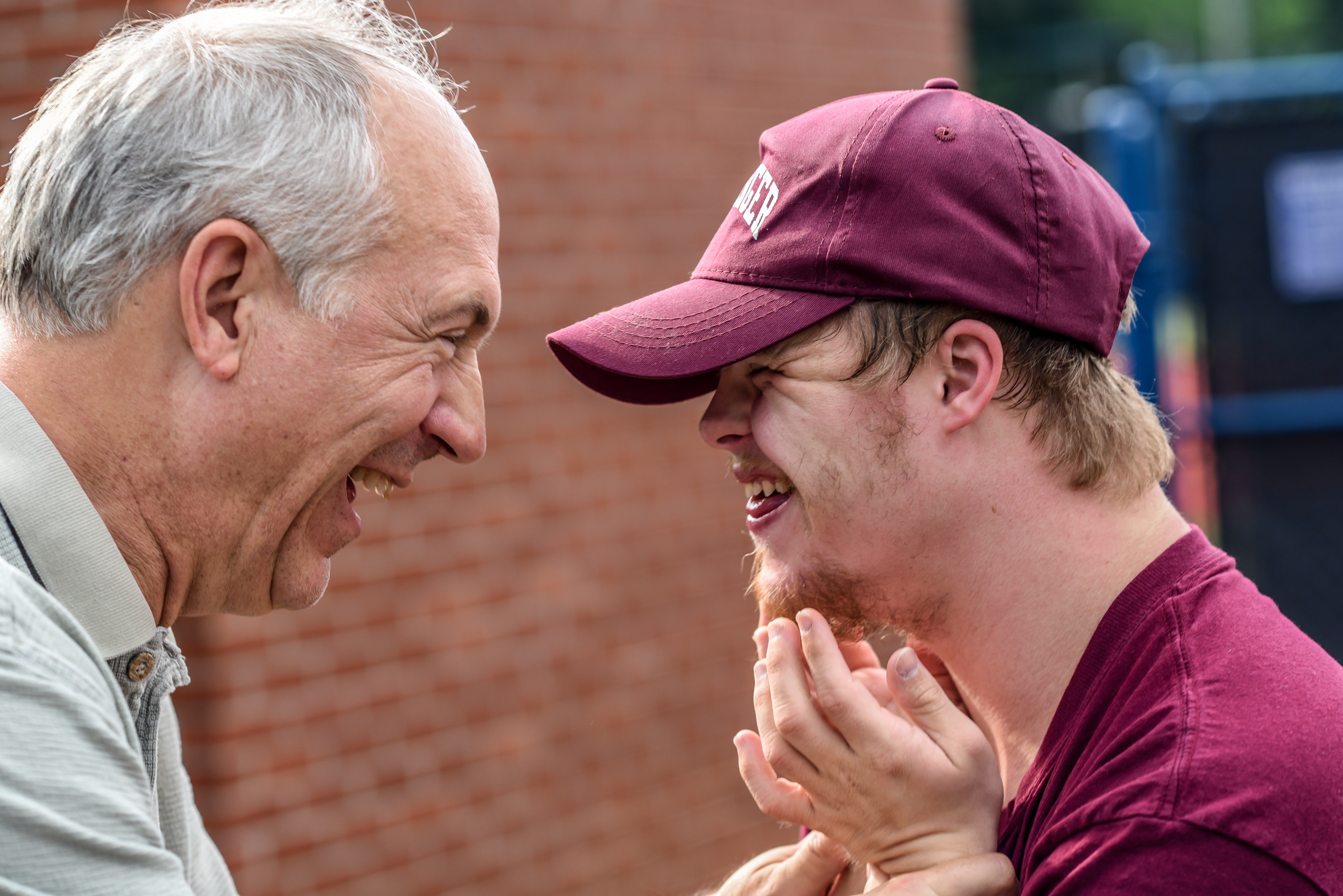 eldery man laughing with a boy with down syndrome